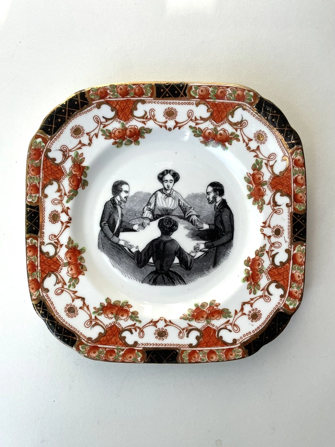 vintage plate with an ornate border, with a printed vintage illustration of a seance in the middle