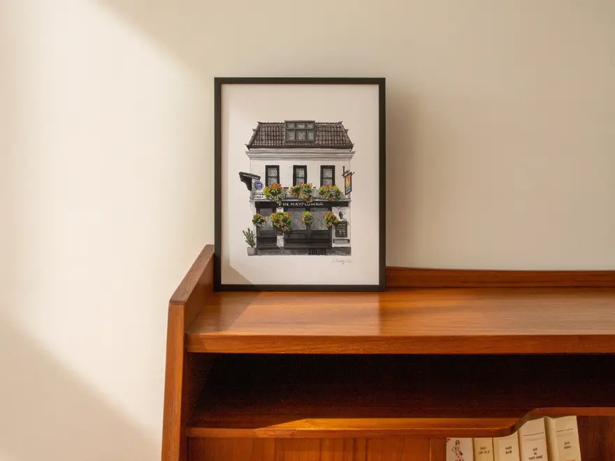 Rotherhithe The Mayflower Pub Giclée Print (Unframed), a print of a pub sitting in a black frame against a wooden surface against a plain backdrop. 