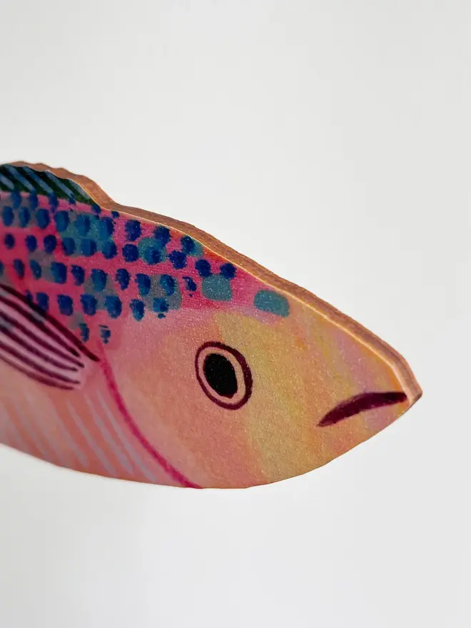 wooden mackerel wall decoration. mackerel decoration hung up on white wall, photographed from the side to show thickness.