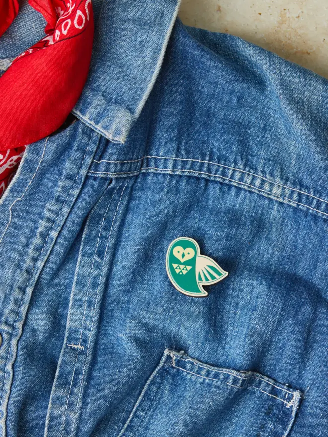 Wooden owl pin badge on a denim jacket