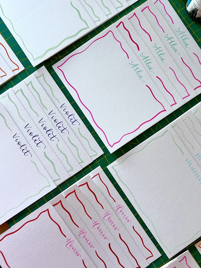 Selection of squiggle border notecards in different colours with names written at the top of each card