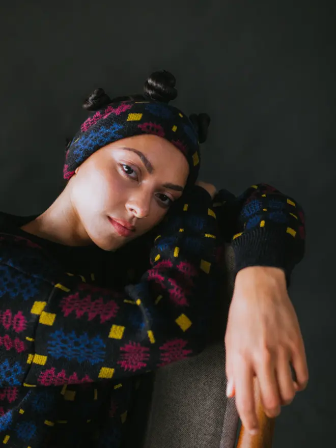 Model wearing pieces from MABLI's 'Carthen' collection, featuring the Carthen Wrap in the vibrant 'Fireworks' colour-way. The design showcases bold, colourful patterns inspired by traditional Welsh blanket tapestry.