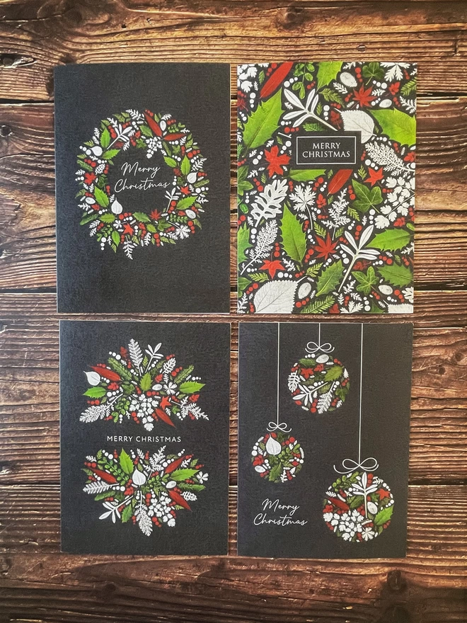 Flat Lay of 4 Christmas Cards with Unique Pressed Winter Leaf Designs, Including Holly and Ivy, on Wooden Background