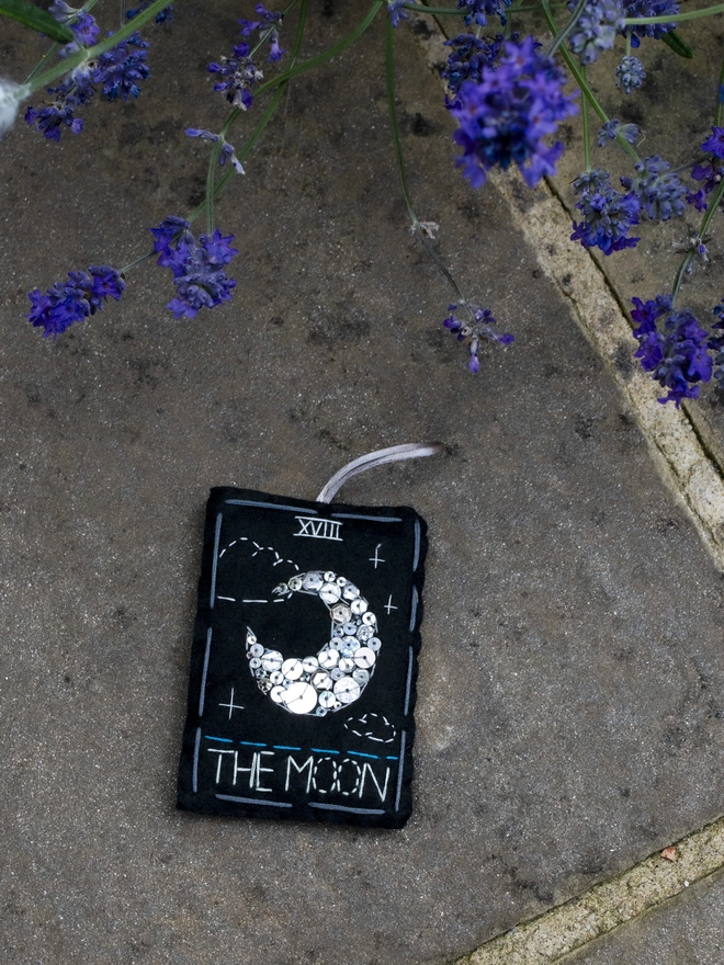 A handcrafted felt ornament with sequins and embroidery depicting "The Moon" tarot card. 