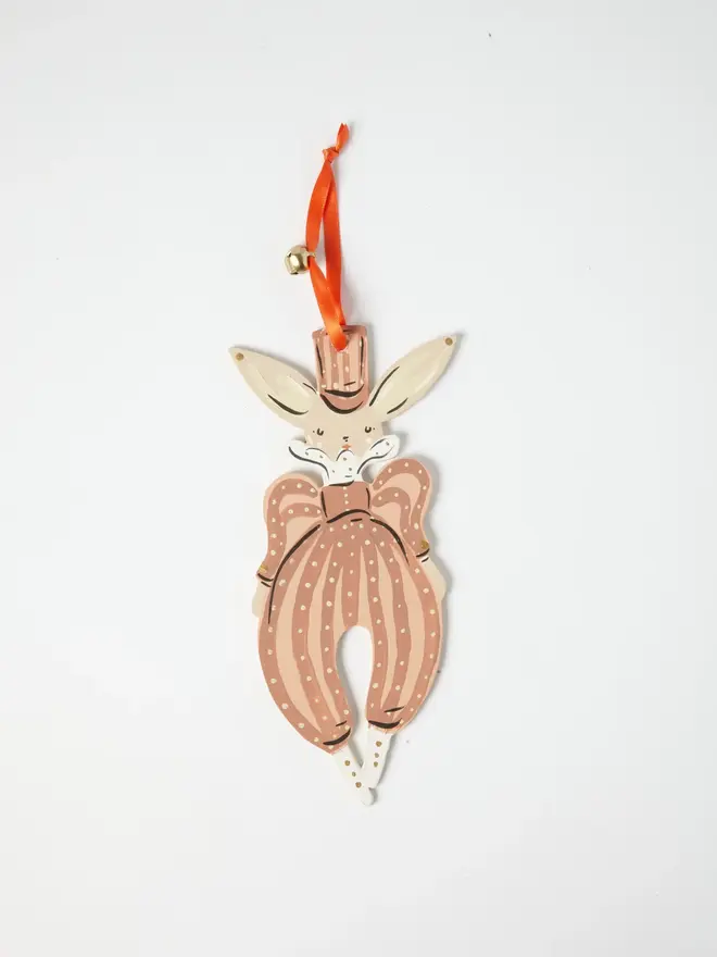Hare Tree Dancer. wooden hanging hare decoration with a pink top hat, dusky pink polka dot pantaloons with a bow, orange ribbon with a jingle bell, on a white background