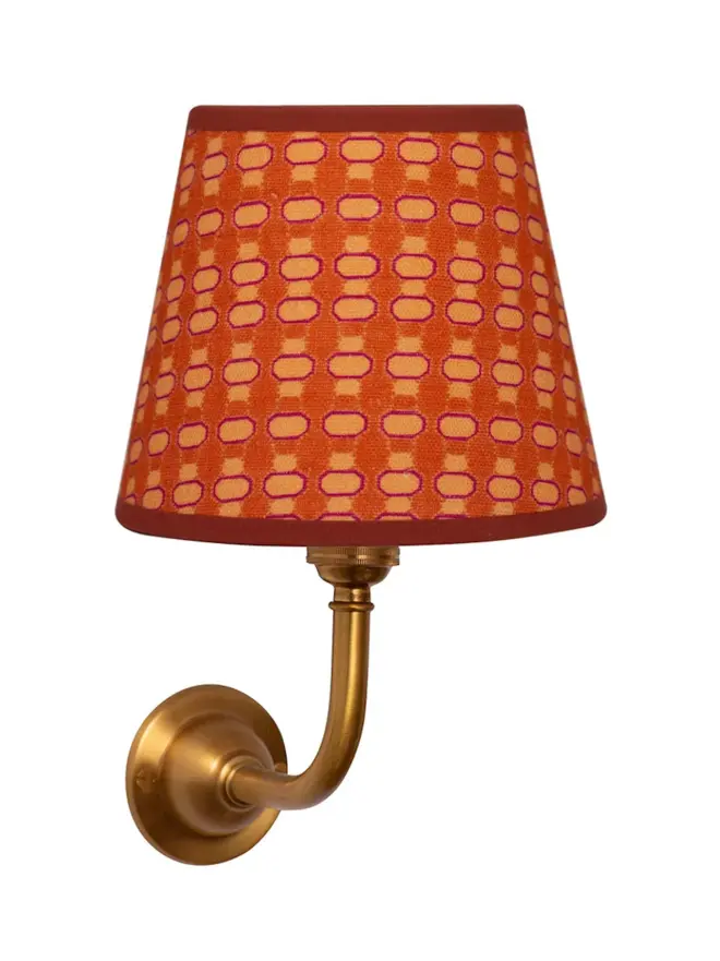 orange lalli patterned lampshade on golden sconce, on white background