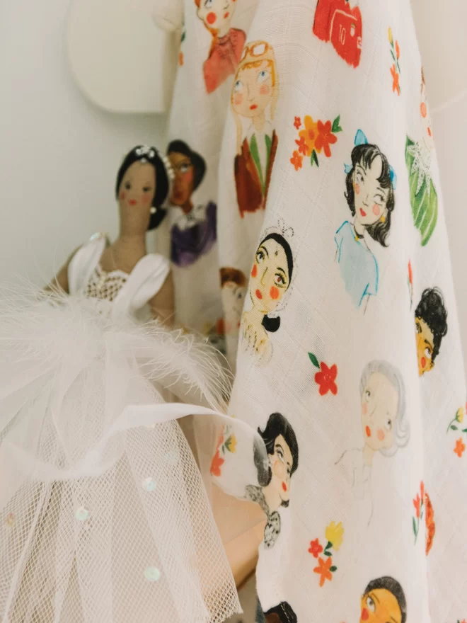 iconic women printed swaddle blanket hanging on hook next to ballerina doll