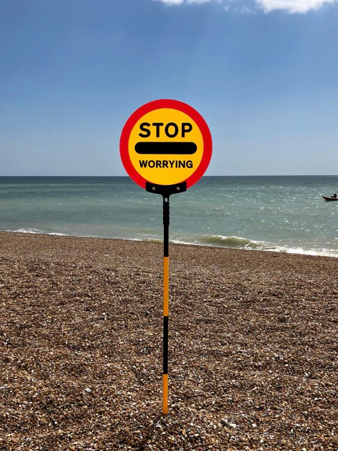 Stop Worrying Sign. A lollipop sign on a beach.