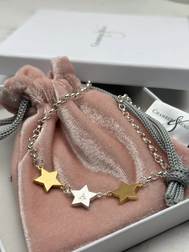 3 chunky star charms hang horizontally from a sterling silver chain.  a personalised silver star hangs in the middle with gold stars on each side