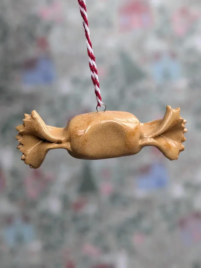 ceramic caramelle hanging christmas decoration. a small ceramic caramelle pasta ornament hanging from red and white thread.