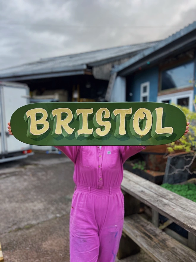 Green skate deck with 'BRISTOL' in casual lettering in gold leaf.