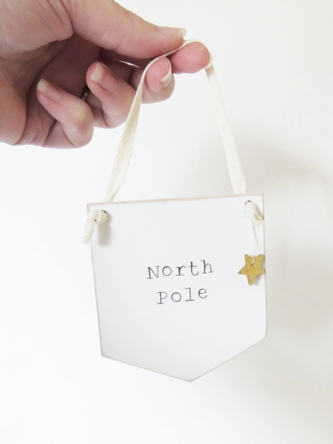 painted white banner with North Pole message strung with cotton and decorated with a wooden gold star.