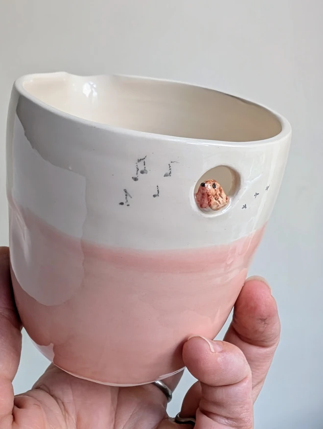 close up of a handmade ceramic white and pink jug with a tiny robin bird in a small cut out hole with bird prints and small musical notes hand painted