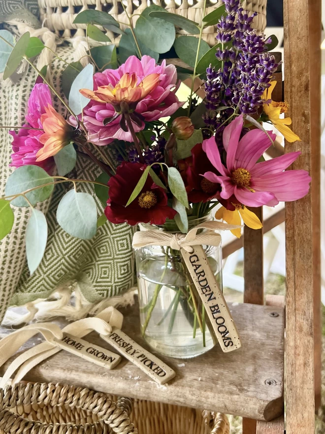 Vase of freshly picked flowers with a ceramic tag tied around the neck