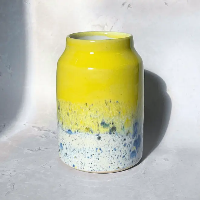 Shoreline Large Vase, a colourful vase placed on a stone surface in front of a plain backdrop. 