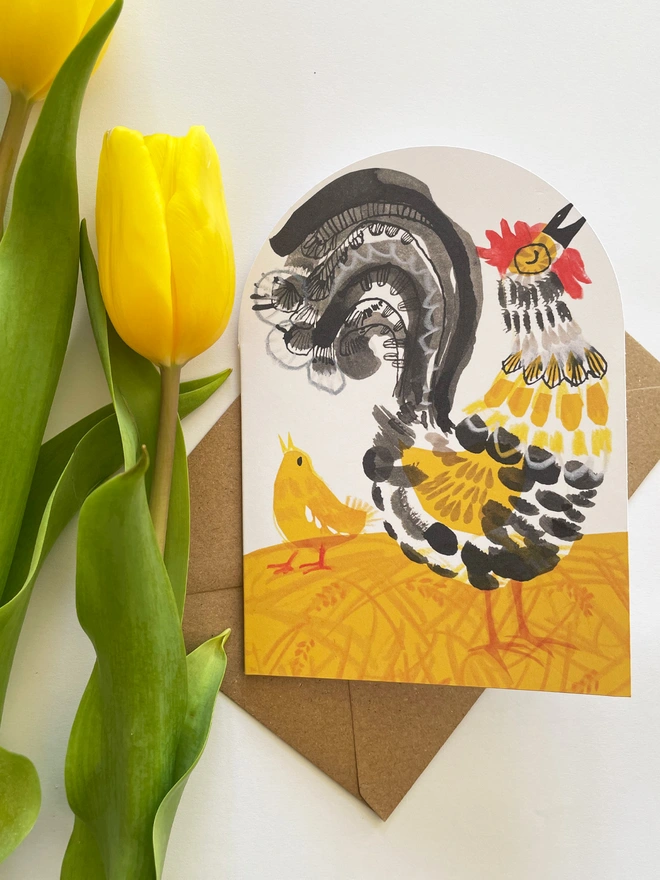 Esther Kent illustrated greeting card showing black, yellow and red stylised cockerel on an arch-shaped card