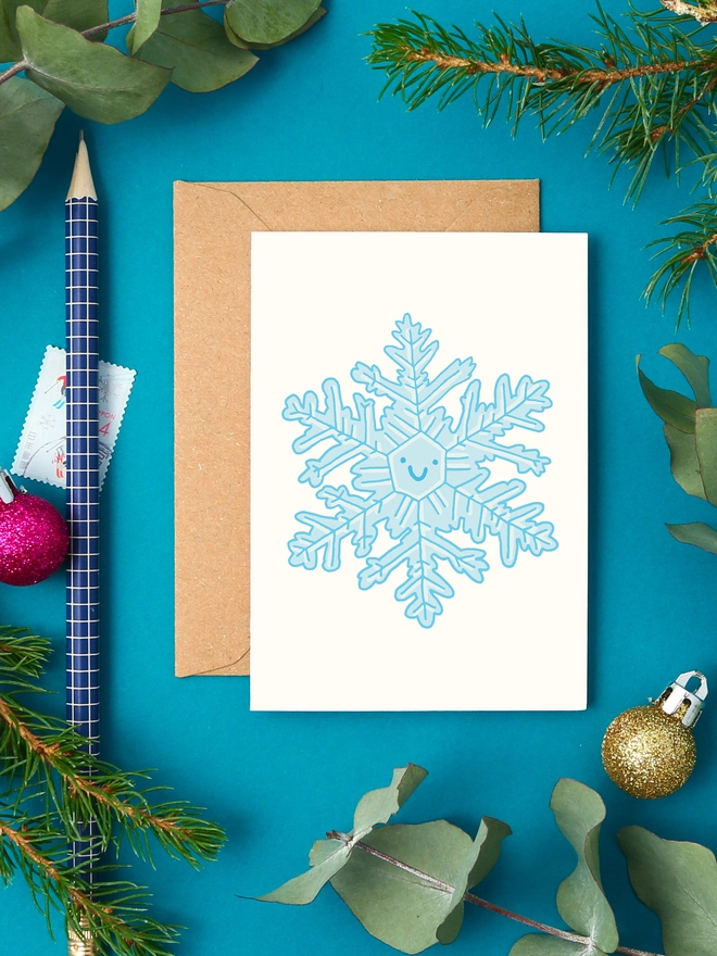 Cute mini Christmas card with a detailed blue snowflake illustration and happy face