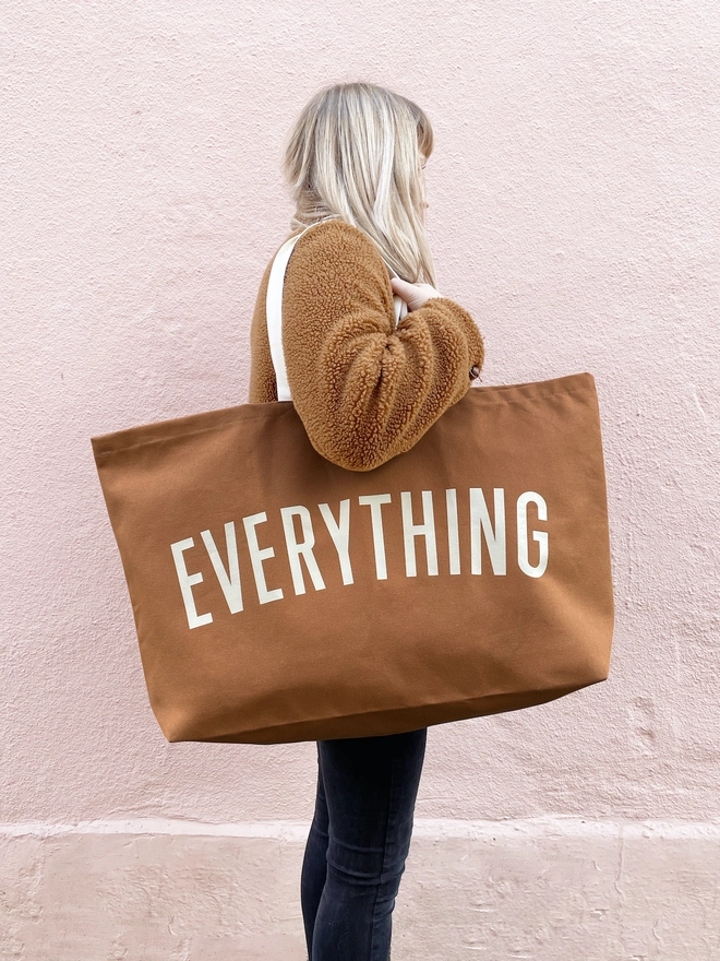 Model holding the Everything oversized tote bag in tan