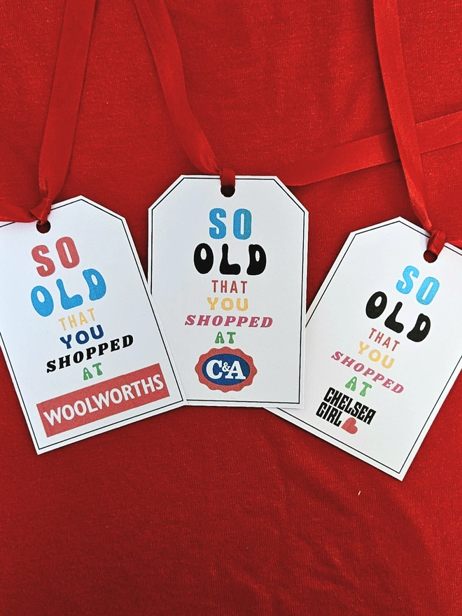3 tags that say so old that you shopped at Woolworths C&A Chelsea Girl in bright colourful letters with a red ribbon