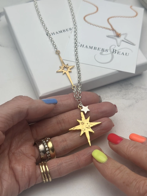 gold north star and overlaid mini star in silver on a sterling silver chain, with linked supernova charm in gold