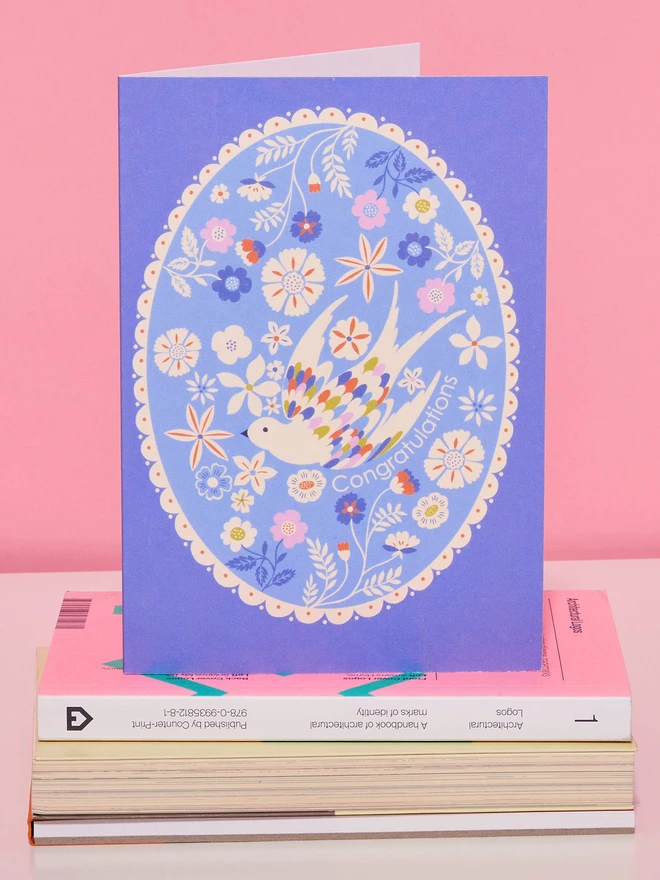purple card with oval design with flowers and birds and 'congratulations' text