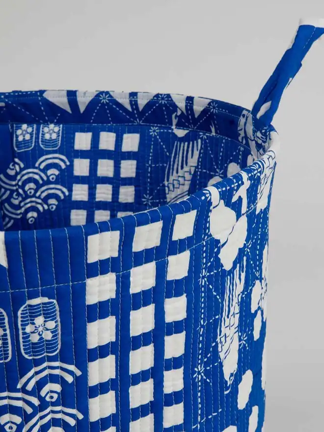 Blue Festival Quilted Storage Basket, a blue basket sitting against a grey backdrop. 