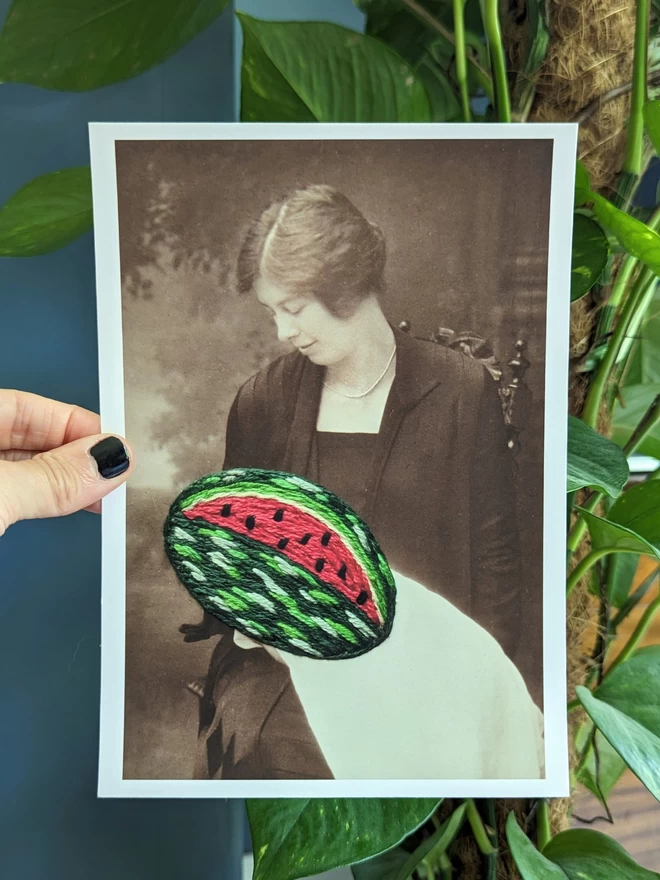 B&W photo print of woman holding embroidered watermelon’ held against blue background