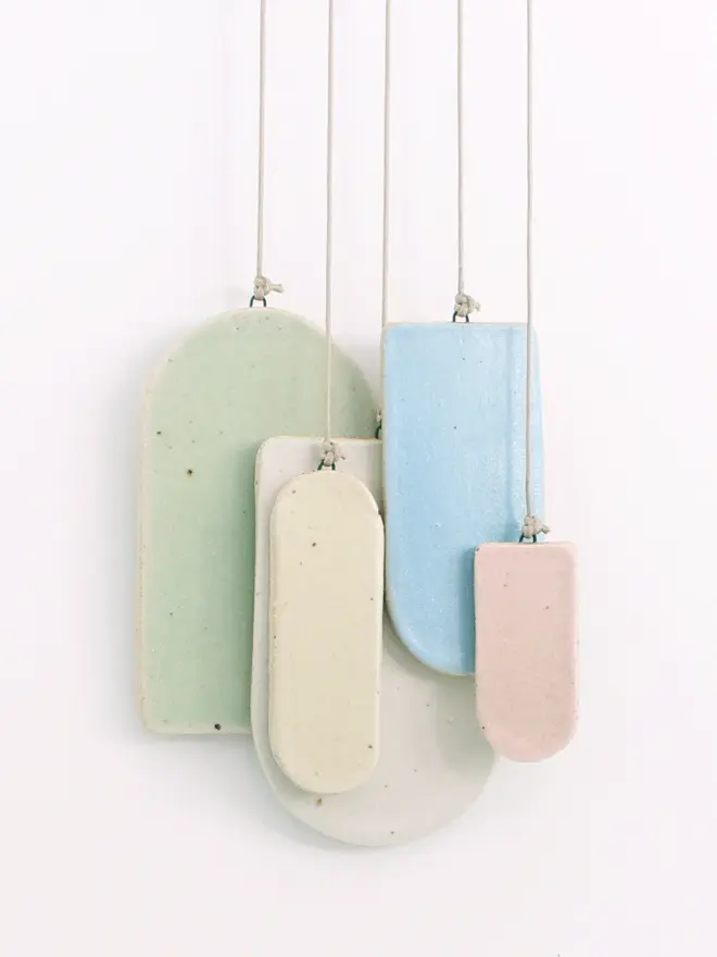 Ceramic arches in different sizes and in pastel white, yellow, mint, pink and blue on cord hanging