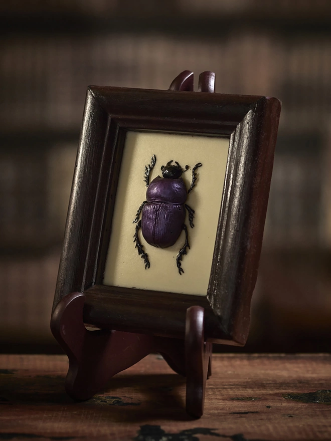 Realistic edible chocolate dung beetle in chocolate frame on antique background