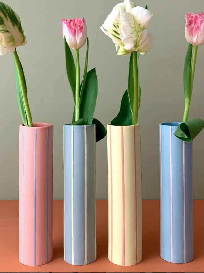 four striped, colourful vases with flower stems in each