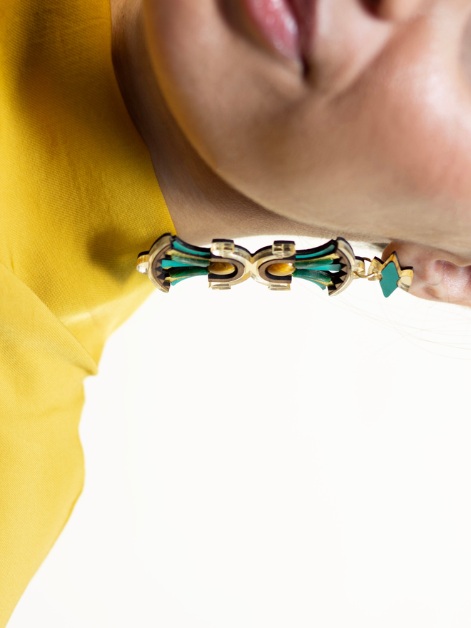 Close-up of a person wearing a gold and green earring with a blurred background