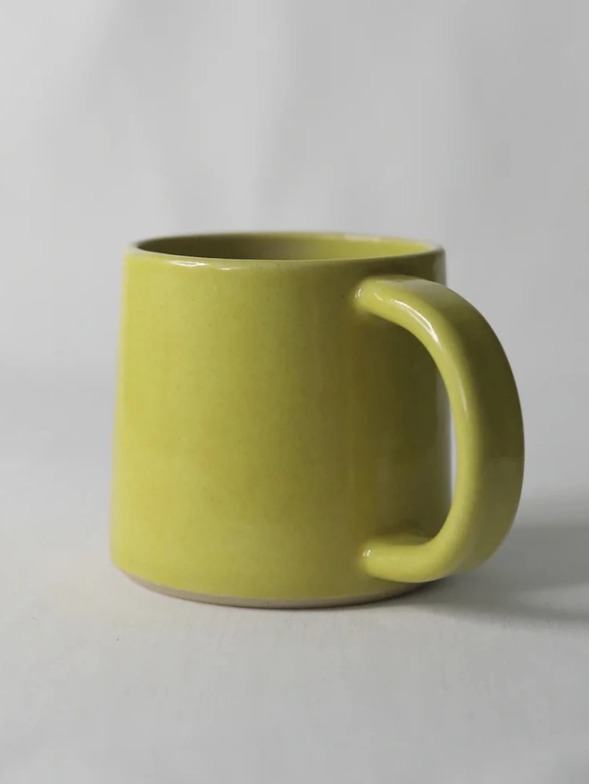 Ceramic Standard Mug, a colourful ceramic mug sitting on a plain surface against a grey backdrop. 