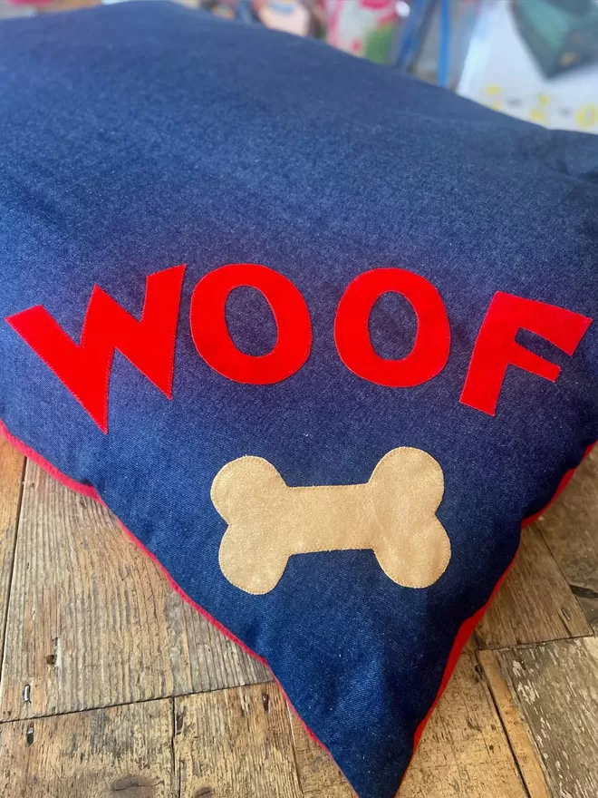 Denim Dog Bed with Red Woof over a tan bone