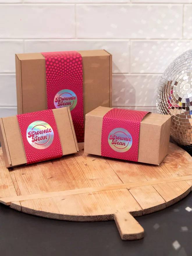 Brownie and the Bean branded packaging on a wooden board with a discoball against a white tiled wall