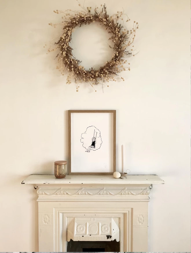 a letter press art print in an oak frame sat on a mantle piece in a white room