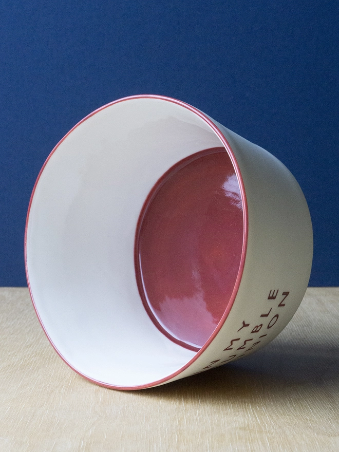 Ceramic porcelain pudding bowl with In My Crumble Opinion written on the side. A white pudding bowl with red rim and interior.