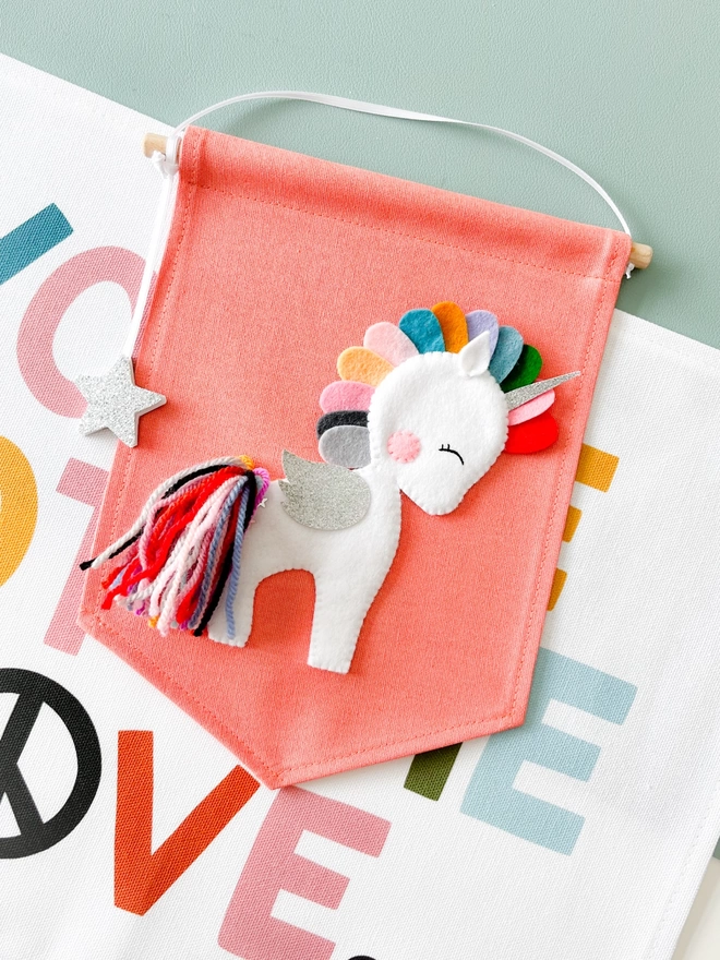 A white unicorn on a canvas banner with a bright mane and tail