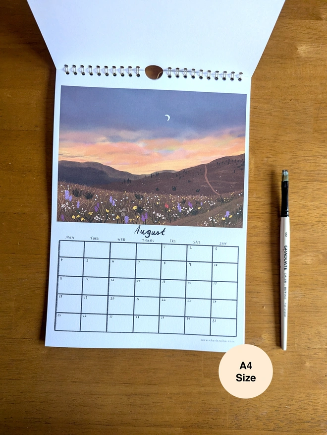 August page of calendar depicts beautiful illustrated sunset, in colours of purple and orange with wildflower meadow.