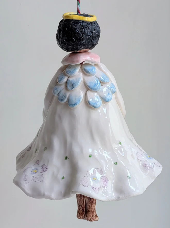 a hanging angel bell decoration with brown skin and violet floral dress in handmade white ceramic