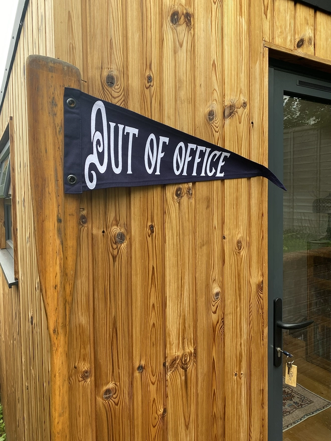 A navy Out of office pennant flag outside and office