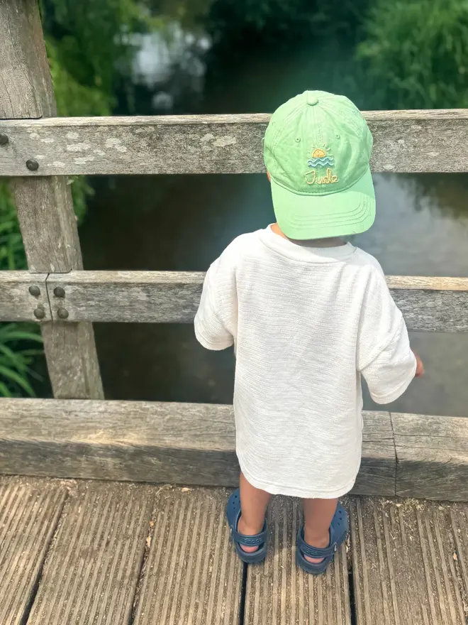 Hand Embroidered Kids Cap, a child standing outside with a personalised cap. 