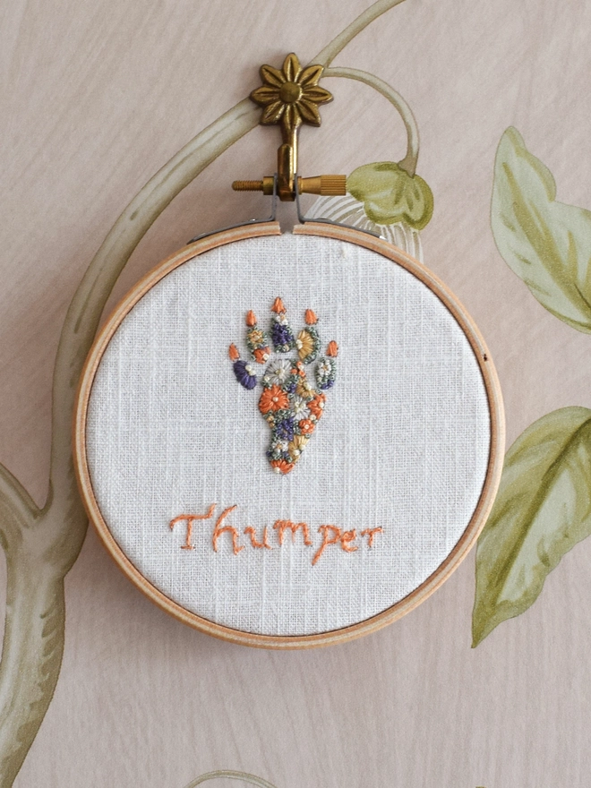 Sunshine Garden Cat Paw of Golden Yellows and Bright Orange Blossoms with Green French Knot grass background.  Displayed in an embroidery hoop on a wall hook.