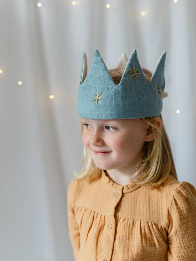 Girl wearing a mustard top and blue crown