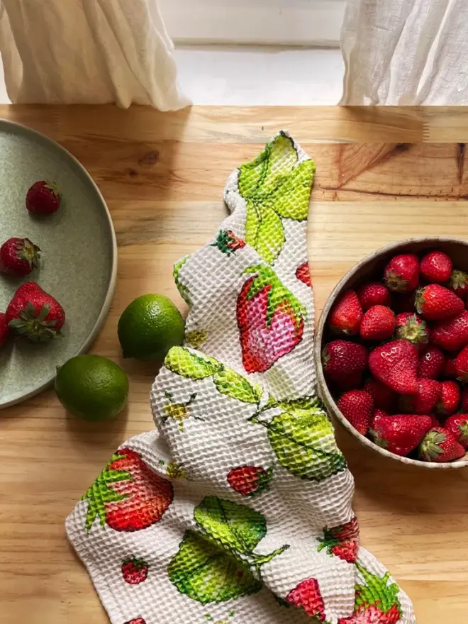 Strawberry Waffle Tea towel, next to a bowl of fruit. 
