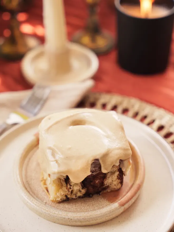 Latte Cinnamon Bun on a neutral coloured plate on a table