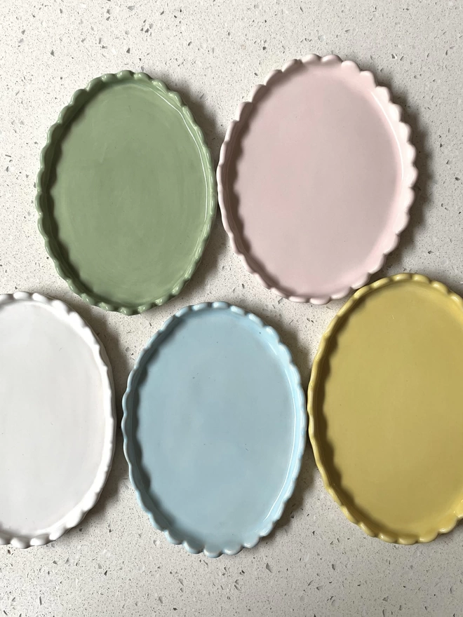 a group of butter dishes with scalloped edge in pastel colours