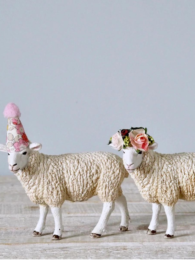 Sheep seen with a floral party hat and a floral headdress.