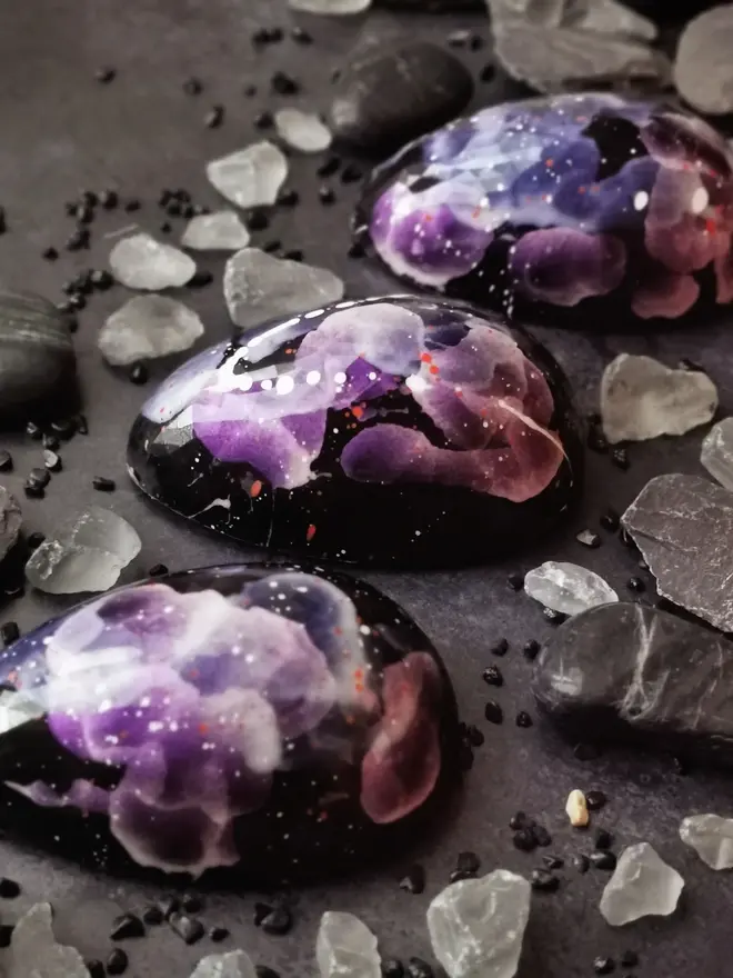 three chocolate easter egg halves, all black with purple floral decor