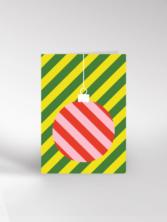 Contemporary illustrated Christmas card featuring a large, stripy bauble