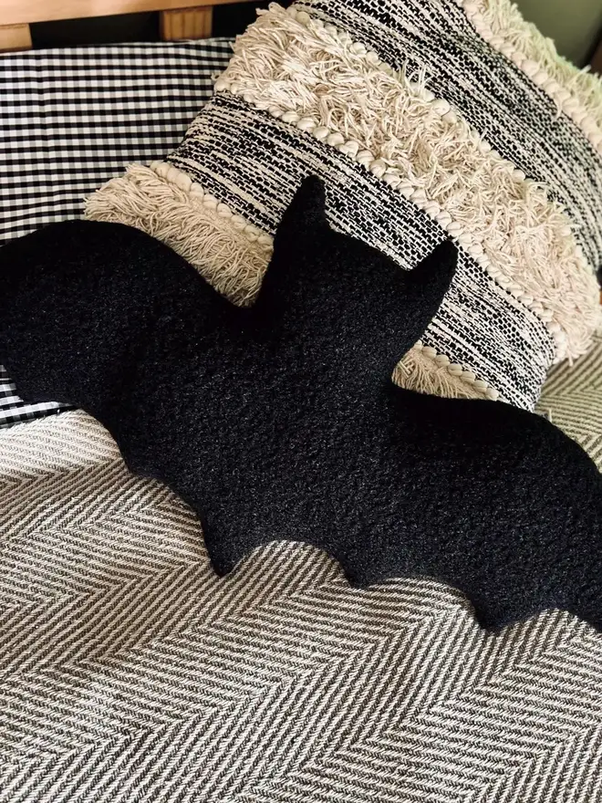 boucle bat pillow. a black cushion shaped like a bat.